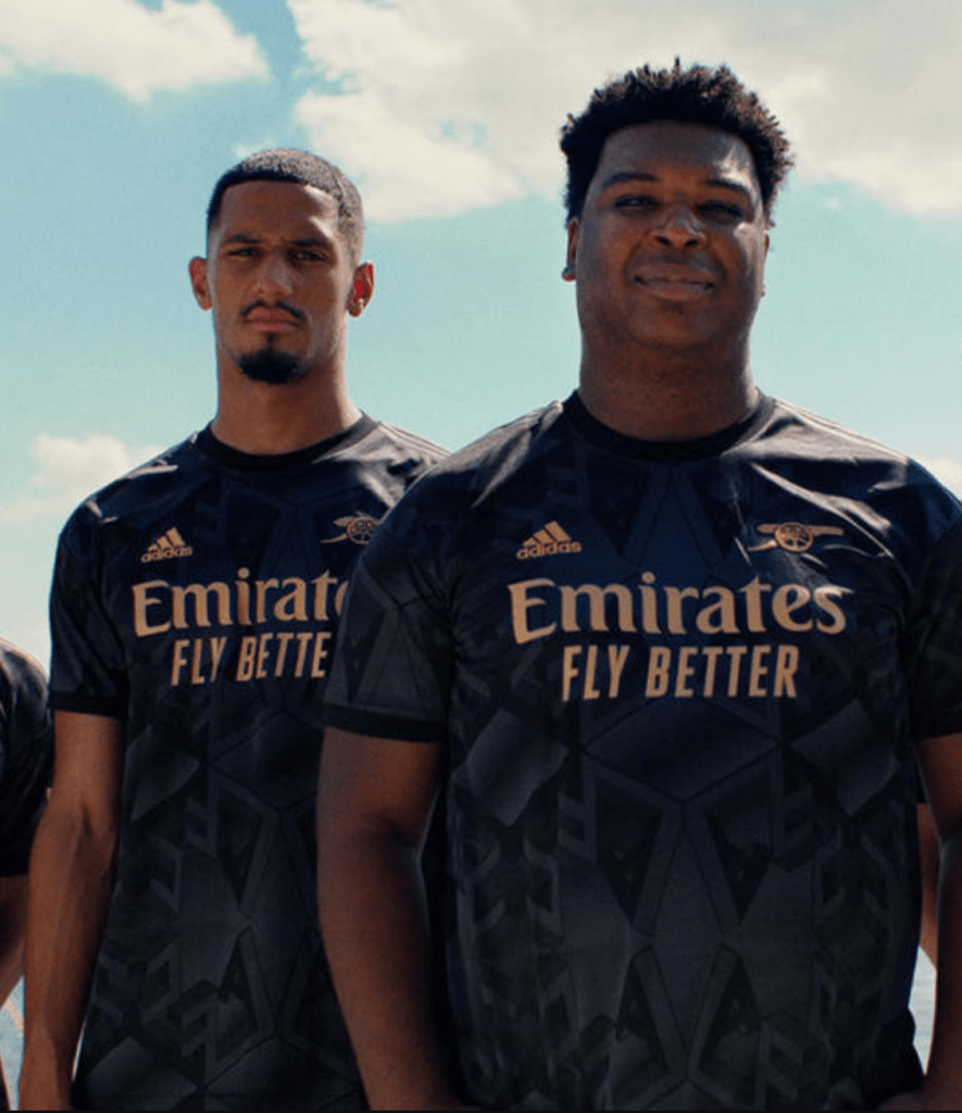 Arsenal 2022-23 black and bronze away shirt, worn by William Saliba and Orlando Freedom Fighters activist Aston Mack. 